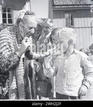 Julia Caesar, 1885-1971. Actrice suédoise dans le rôle de Miss Lur, lors du tournage du film Kastrullresan de 1950. Avec l'aide d'une trompette d'oreille, elle peut entendre mieux et un garçon peut être vu jouer pour elle droit dans elle. réf. BV2-11 Banque D'Images