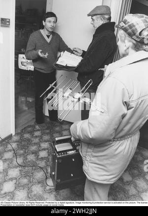 Détecteur TV en cours d'utilisation. Dans les années 1980 et 1990, les personnes qui n'avaient pas déclaré avoir un téléviseur étaient contrôlées par télésurveillance pour déterminer si un ménage avait un récepteur de télévision ou non. Le but de l'activité était de trouver des ménages qui possédaient un récepteur de télévision sans licence de télévision payante. Avec une antenne directionnelle, l'inspecteur reçoit les signaux dans l'équipement de mesure qui montre que le propriétaire de l'appartement a une télévision sans payer de frais à l'État pour cela. Voici un homme qui a probablement du mal à parler de son moyen de sortir de la situation quand le téléviseur est visibl Banque D'Images