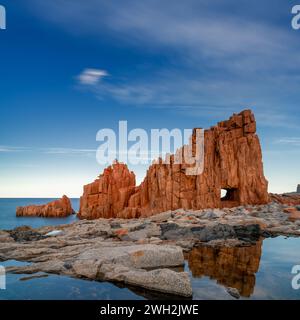 Une vue des roches rouges d'Arbatax avec des reflets dans les bassins de marée au premier plan Banque D'Images