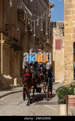 Mdina, Malte - 22 décembre 2023 : carrossier conduisant des touristes dans une calèche dans la vieille ville de Mdina à Malte Banque D'Images