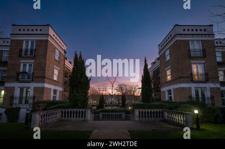 Bâtiments modernes et arbres dans la soirée. Vue grand angle au crépuscule avec ciel bleu foncé et nuages roses. Banque D'Images