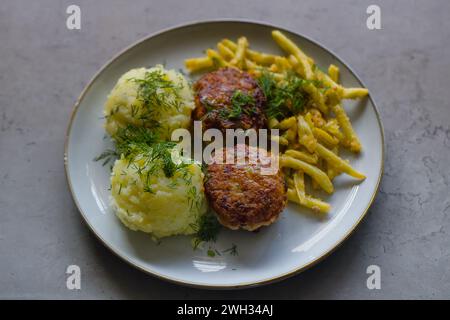 Cuisine polonaise classique : hamburgers hachés de porc, purée de pommes de terre, haricots jaunes, chapelure, garnie d'aneth finement haché. Banque D'Images