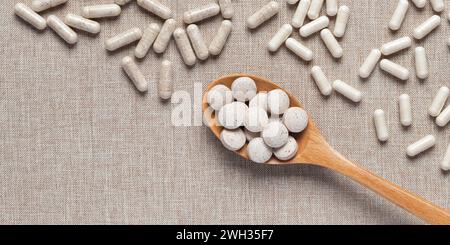 Compléments alimentaires organiques en capsules sur fond de tissu beige. Vitamines et bioadditifs naturels en comprimés. Différentes pilules médicales sur table. EM Banque D'Images