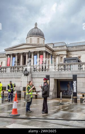 Manipulateur d'oiseaux Hawk à Trafalgar Square défrichant des pigeons et parlant à un gardien du patrimoine. Banque D'Images