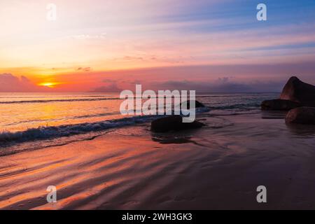 Paysage balnéaire avec sable humide et pierres côtières. Coucher de soleil à beau Vallon Beach, Seychelles Banque D'Images