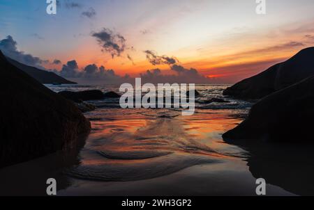 Photo de paysage balnéaire avec du sable humide et des pierres côtières sur le coucher du soleil. Plage de beau Vallon, Seychelles Banque D'Images