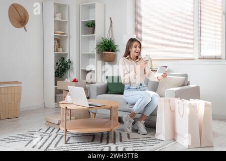 Jeune femme prenant une photo de carte-cadeau à la maison Banque D'Images