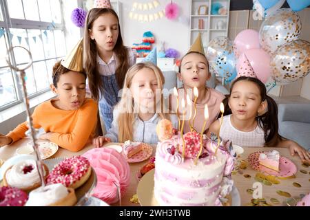Petits enfants mignons soufflant des bougies sur le gâteau d'anniversaire à la fête Banque D'Images