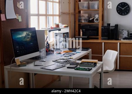 Lieu de travail du réparateur électronique en atelier avec des outils et des éléments informatiques démontés sur table Banque D'Images