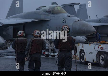 240205-N-LM220-1147 OCÉAN PACIFIQUE (5 février 2024) des marins se préparent à caler et à enchaîner un F/A-18E Super Hornet, affecté au Strike Fighter Squadron (VFA) 14, sur le pont d'envol du porte-avions USS Abraham Lincoln de classe Nimitz (CVN 72). Le Abraham Lincoln Carrier Strike Group est en cours dans la zone d'opérations de la 3rd Fleet des États-Unis menant une formation tactique avancée qui augmente la capacité de combat et les compétences tactiques dans tous les domaines. (Photo de l'US Navy par Clayton A. Wren, spécialiste des communications de masse, 2e classe) Banque D'Images