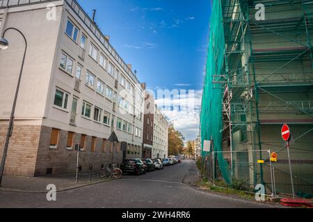 Photo d'un quartier résidentiel de Cologne, en Allemagne, avec des voitures garées dans une rue déserte, des bâtiments à plusieurs étages et des projets de rénovation en co Banque D'Images