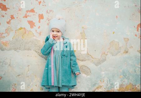 mode automne. journée des enfants. petite fille en manteau vintage sur fond grunge. Beauté. style rétro. copier l'espace. petits vêtements de printemps pour enfants. heureux Banque D'Images