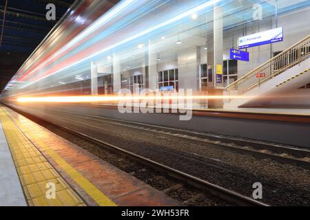 Image lente et longue exposition d'un train rapide passant devant une gare de Palmerah, Jakarta. Ligne commuter Indonésie. Convient pour papier peint, affiche. Banque D'Images
