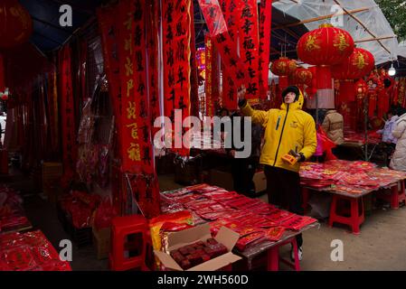 Le nouvel an lunaire 2024 approche à grands pas. Un livreur de plats à emporter Meituan choisit les couplets du nouvel an sur un marché du nouvel an lunaire Banque D'Images