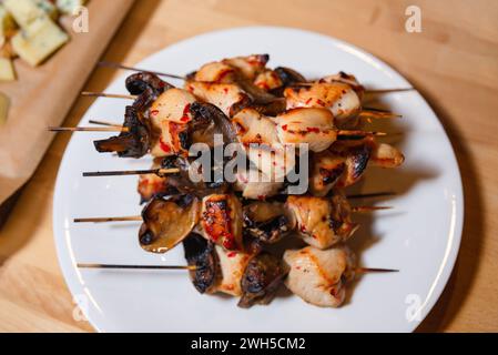 Brochettes de poulet grillé et de champignons juteuses servies sur une assiette blanche, parfaites pour un délicieux apéritif ou un plat principal Banque D'Images