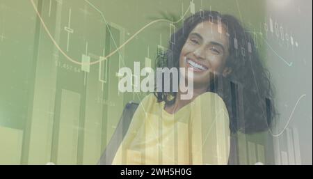 Image du traitement des données financières sur la femme d'affaires biraciale souriante Banque D'Images