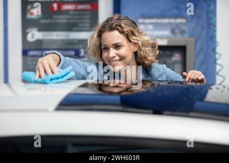 une femme essuyant la surface de la voiture par tissu de micro fibre Banque D'Images