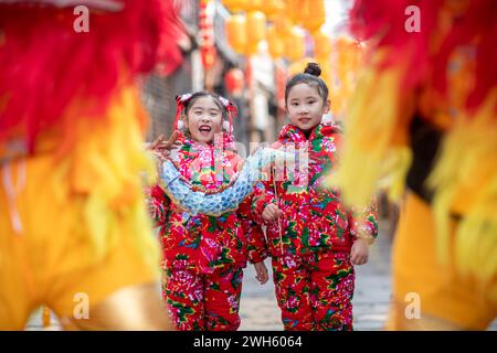 Xingyi, Chine. 08th Feb, 2024. Les enfants regardent un lion danser dans la zone de tourisme culturel et de loisirs Baziqiao de la rue Zhaoyang à Xinghua, en Chine, le 8 février 2024. (Photo de Costfoto/NurPhoto) crédit : NurPhoto SRL/Alamy Live News Banque D'Images