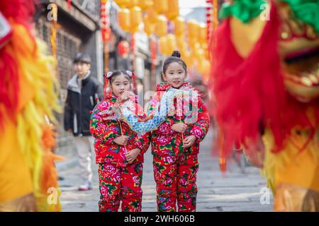 Xingyi, Chine. 08th Feb, 2024. Les enfants regardent un lion danser dans la zone de tourisme culturel et de loisirs Baziqiao de la rue Zhaoyang à Xinghua, en Chine, le 8 février 2024. (Photo de Costfoto/NurPhoto) crédit : NurPhoto SRL/Alamy Live News Banque D'Images