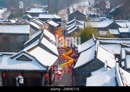Suqian, Chine. 08th Feb, 2024. Une lanterne dragon géante se distingue du paysage enneigé et des bâtiments anciens sur la rue Huangpai dans le comté de Xuyi de la ville de Huai'an, à Suqian, en Chine, le 7 février 2024. Les touristes prennent des photos et découvrent la saveur du nouvel an lunaire. (Photo de Costfoto/NurPhoto) crédit : NurPhoto SRL/Alamy Live News Banque D'Images