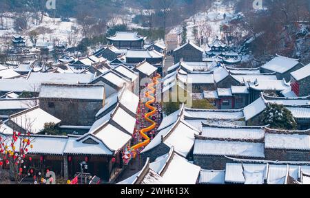 Suqian, Chine. 08th Feb, 2024. Une lanterne dragon géante se distingue du paysage enneigé et des bâtiments anciens sur la rue Huangpai dans le comté de Xuyi de la ville de Huai'an, à Suqian, en Chine, le 7 février 2024. Les touristes prennent des photos et découvrent la saveur du nouvel an lunaire. (Photo de Costfoto/NurPhoto) crédit : NurPhoto SRL/Alamy Live News Banque D'Images