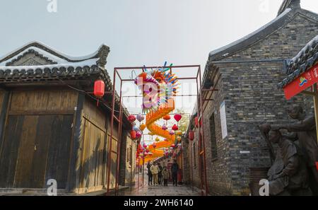 Suqian, Chine. 08th Feb, 2024. Une lanterne dragon géante se distingue du paysage enneigé et des bâtiments anciens sur la rue Huangpai dans le comté de Xuyi de la ville de Huai'an, à Suqian, en Chine, le 7 février 2024. Les touristes prennent des photos et découvrent la saveur du nouvel an lunaire. (Photo de Costfoto/NurPhoto) crédit : NurPhoto SRL/Alamy Live News Banque D'Images