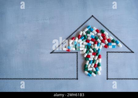 Flèche pointant vers le haut et un tas de pilules colorées. Demande élevée, coût croissant des médicaments sur ordonnance concept. Banque D'Images