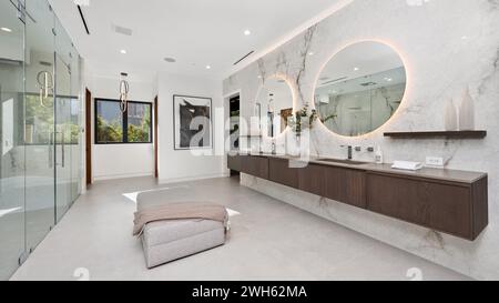 Une salle de bains spacieuse avec deux lavabos, une douche à l'italienne et d'élégants miroirs Banque D'Images