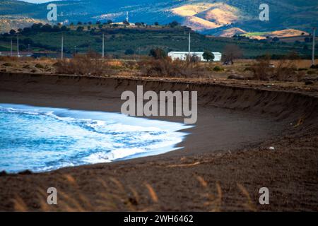 Une scène côtière tranquille avec des rives sablonneuses et des roseaux, offrant un paysage serein et naturel le long de la belle côte. Banque D'Images