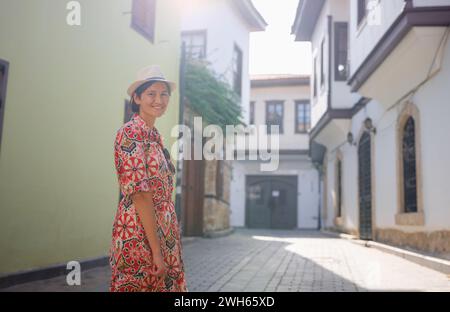 Voyage d'été féminin à Antalya, Turquie. Jeune femme asiatique en robe rouge marcher à travers la vieille ville Kalechi , voyageur touristique féminin découvrir des endroits intéressants et attraction touristique populaire Banque D'Images