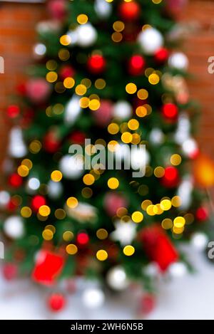 Un sapin de Noël festif hors de propos, créant un beau motif abstrait de lumières bokeh colorées contre un mur de briques. Banque D'Images