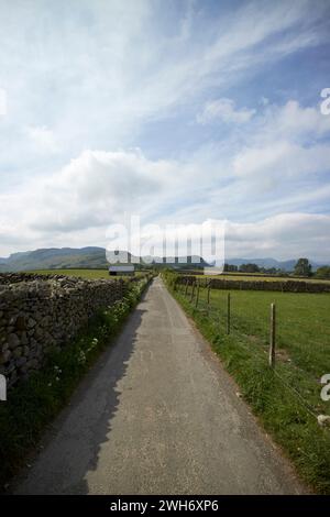 Tarmaced country lane bordée par un mur en pierre sèche et clôture métallique en milieu rural underskiddaw Keswick Cumbria england uk Banque D'Images