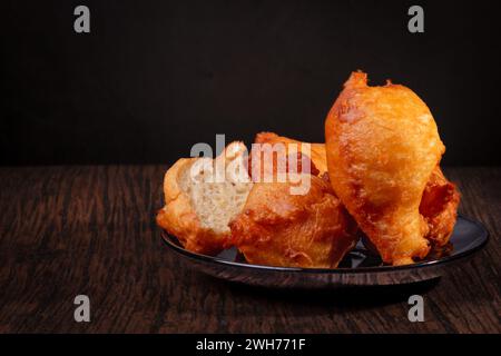 Crêpes de levure sur une plaque noire. Fond sombre, planche en bois. Pâtisseries polonaises. Fin du carnaval, beignets. Gros jeudi. Banque D'Images