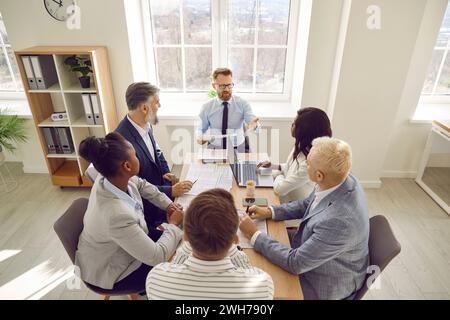 Groupe de gens d'affaires divers communiquant tout en étant assis au bureau ensemble Banque D'Images