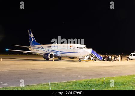 Bichkek, Kirghizistan - 26 septembre 2023 : des gens marchent dans les escaliers aériens pour aller à l'avion de trafic Avia à l'aéroport international de Manas la nuit Banque D'Images