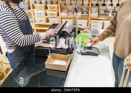 Femme payant par carte de crédit dans une épicerie locale zéro déchet à la caisse Banque D'Images