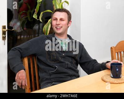 Portrait de jeune homme assis à table en conversation avec une Coupe de thé Surrey Angleterre Banque D'Images