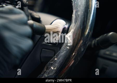 Homme dans des gants de protection effectue des détails dans l'intérieur de la voiture Banque D'Images