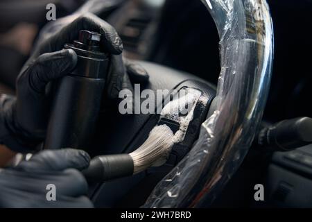 Le spécialiste portant des gants de protection effectue les détails à l'intérieur de la voiture Banque D'Images