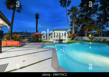 Une grande piscine turquoise entourée de chaises longues et de palmiers Banque D'Images