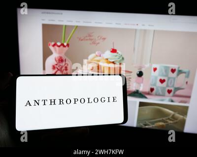 Personne tenant le téléphone portable avec le logo de la société américaine de vente au détail de vêtements Anthropologie Inc en face de la page Web. Concentrez-vous sur l'affichage du téléphone. Banque D'Images