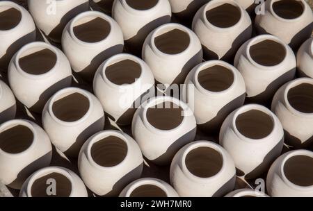 Rangées de pots en argile faits à la main à vendre sur un marché marocain créant un motif géométrique de lumière et d'obscurité Banque D'Images