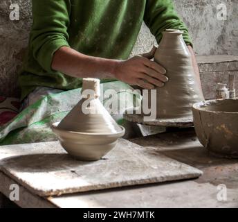 Main de potier marocain jetant un pot en argile tagine à vendre sur le marché Banque D'Images