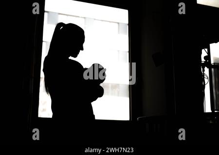Brême, Allemagne. 08th Feb, 2024. Une femme se tient avec un nouveau-né à la fenêtre de l'hôpital. Brême veut améliorer les conditions de travail des infirmières et des sages-femmes avec un projet pilote dans un hôpital. Le 'je m'allaite à nouveau parce que.' Le projet a été lancé début février au sein du Collège L'hôpital Joseph-Stift de Brême. Au cours des quatre prochaines années, l'objectif est de travailler avec les infirmières et les sages-femmes pour améliorer les conditions de travail dans la salle d'accouchement et la maternité. Crédit : Sina Schuldt/dpa/Alamy Live News Banque D'Images