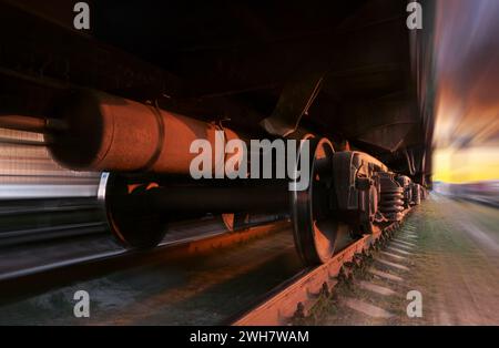 Train de marchandises en mouvement sur fond d'un beau coucher de soleil avec un effet flou. Vue en angle bas. Banque D'Images