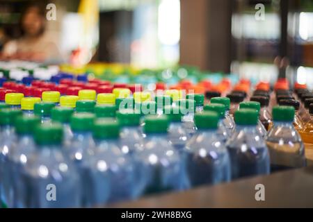 Lot de bouteilles d'eau minérale de petit volume en plastique bleu d'un demi-litre, bouchon rouge jaune vert dans le magasin, étagère de supermarché, gros plan. plasti haute consommation Banque D'Images