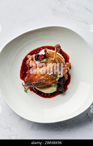 Cuisse de canard rôtie, confite, purée de panais, chipolata de porc épicé et de graines de fenouil, bulbe de fenouil rôti, jus de canard, mûres de boysen Banque D'Images