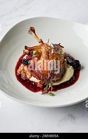 Cuisse de canard rôtie, confite, purée de panais, chipolata de porc épicé et de graines de fenouil, bulbe de fenouil rôti, jus de canard, mûres de boysen Banque D'Images