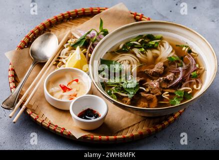 Pho Bo soupe vietnamienne avec du bœuf dans un plateau sur fond béton Banque D'Images