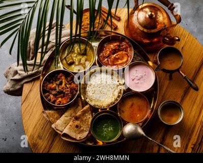 Cuisine indienne Thali repas de style indien avec de la viande de poulet et du thé Masala Chai sur une table en bois Banque D'Images